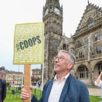 Comedian and Actor Steve Coogan holding a hashtag coop sign outside Coop Congress 2025