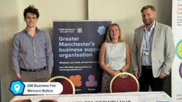 Three staff standing in front of a banner stating services offered e.g., funding 