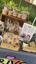 Close-up image of Thrive CIC's products for sale on display. The table shows handmade decorative items and a holder explaining the organisation's mission.
